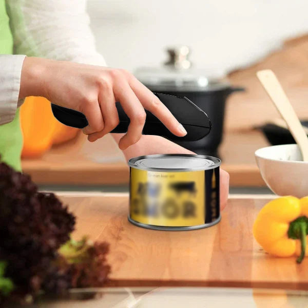 Automaattinen ruostumaton teräspurkkiavaaja käytössä, musta ergonominen kahva, helppokäyttöinen keittiöväline.